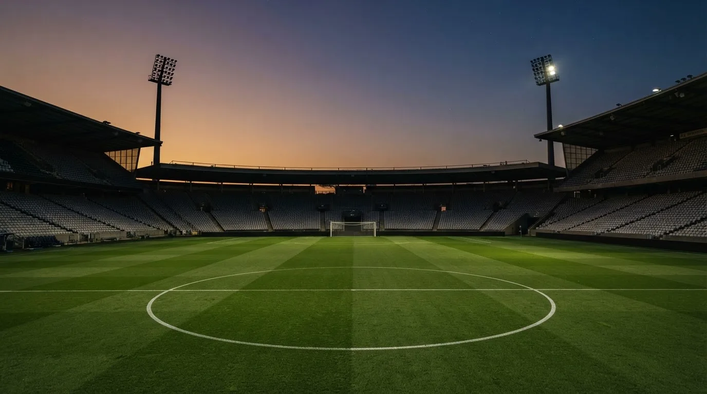 Een leeg voetbalstadion met lichtmasten bij schemering