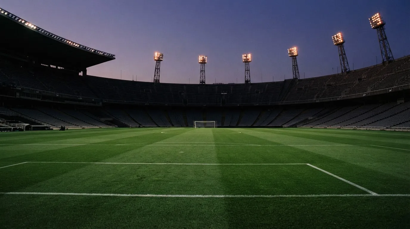 Een leeg voetbalstadion met lichtmasten bij schemering