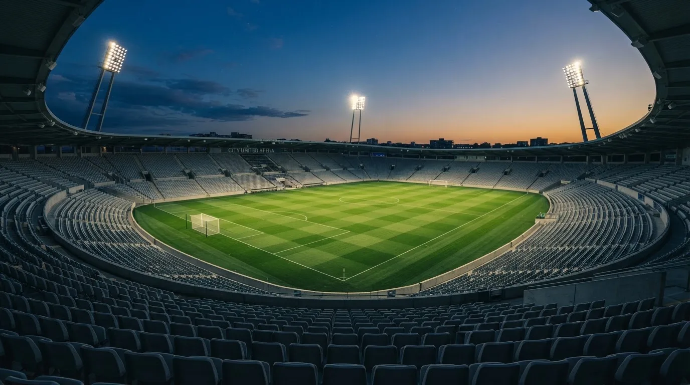 Een leeg voetbalstadion met lichtmasten bij schemering