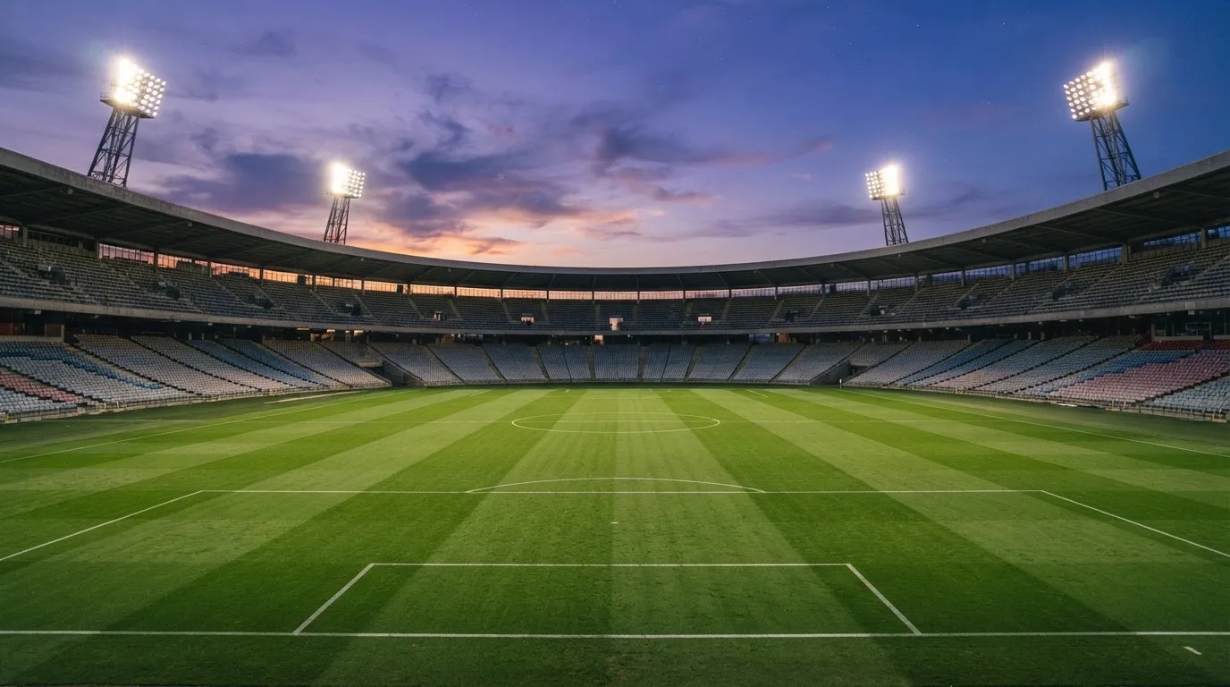 Een leeg voetbalstadion met lichtmasten bij schemering