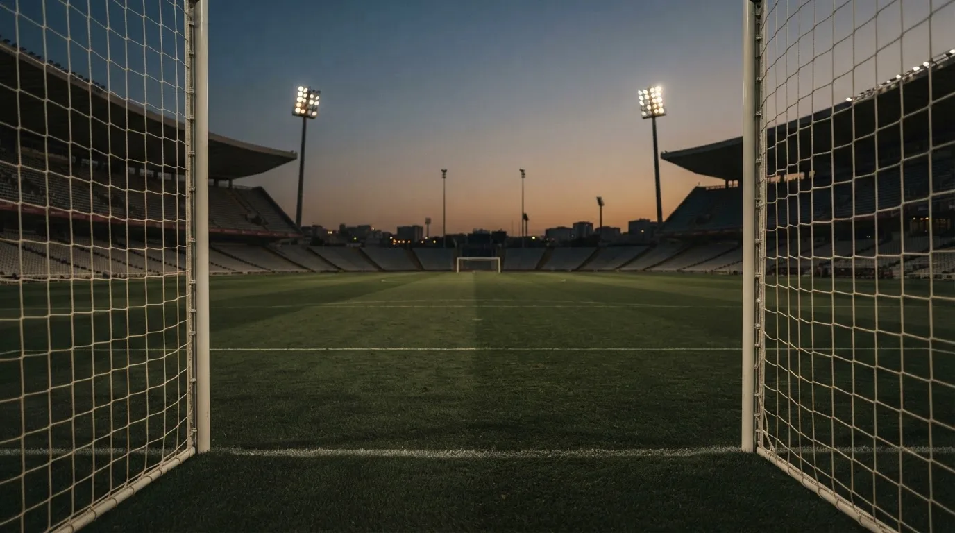 Een leeg voetbalstadion met lichtmasten bij schemering