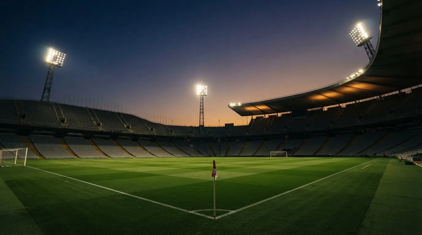Een leeg voetbalstadion met lichtmasten bij schemering
