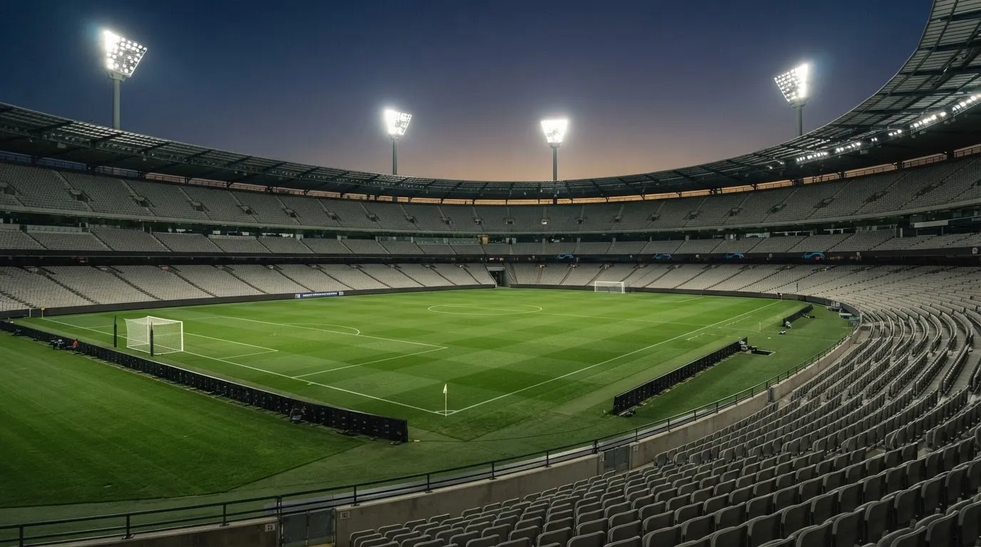 Een leeg voetbalstadion met lichtmasten bij schemering