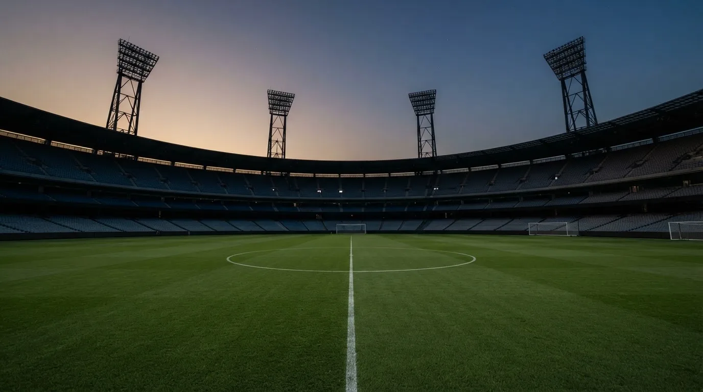 Een leeg voetbalstadion met lichtmasten bij schemering