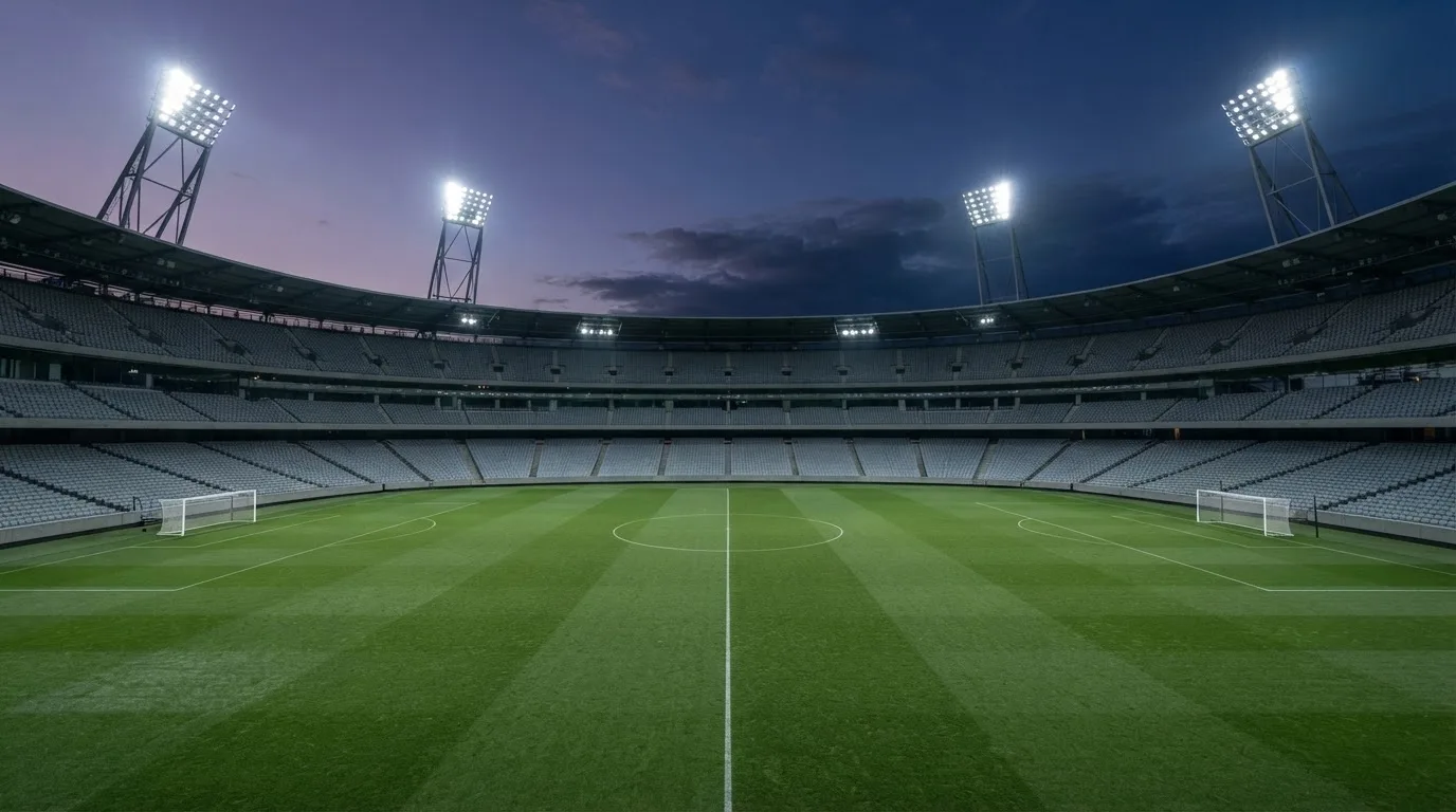 Een leeg voetbalstadion met lichtmasten bij schemering
