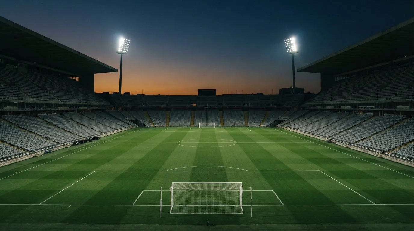 Een leeg voetbalstadion met lichtmasten bij schemering