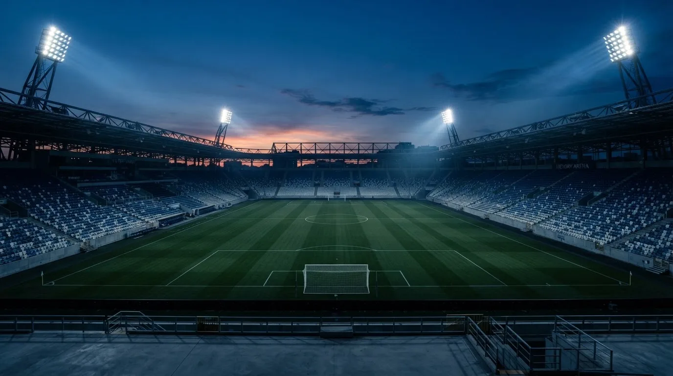 Een leeg voetbalstadion met lichtmasten bij schemering