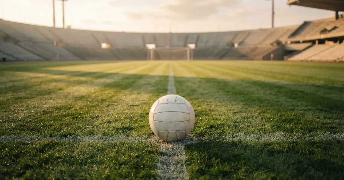 Een voetbal op de middenstip van een grasveld in het ochtendlicht