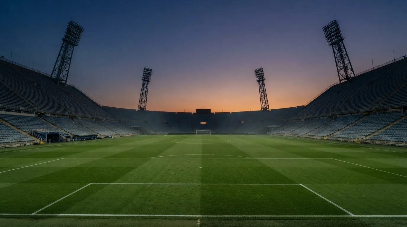 Een leeg voetbalstadion met lichtmasten bij schemering