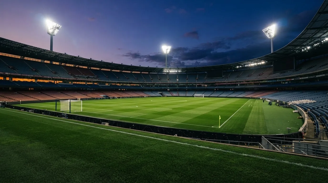 Een leeg voetbalstadion met lichtmasten bij schemering