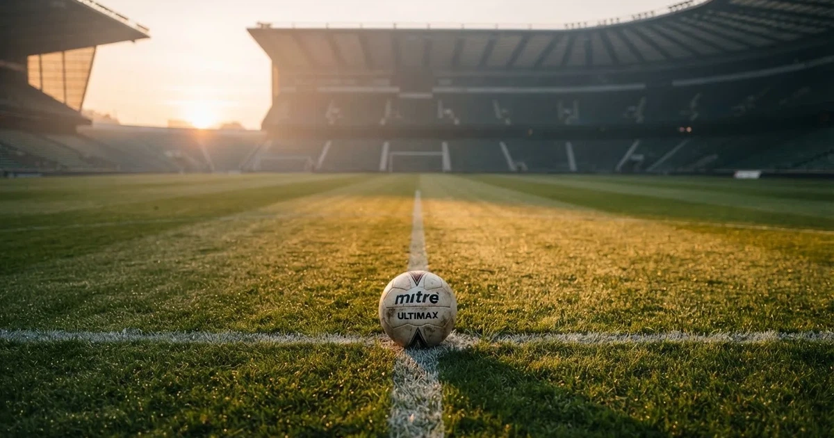 Een voetbal op de middenstip van een grasveld in het ochtendlicht