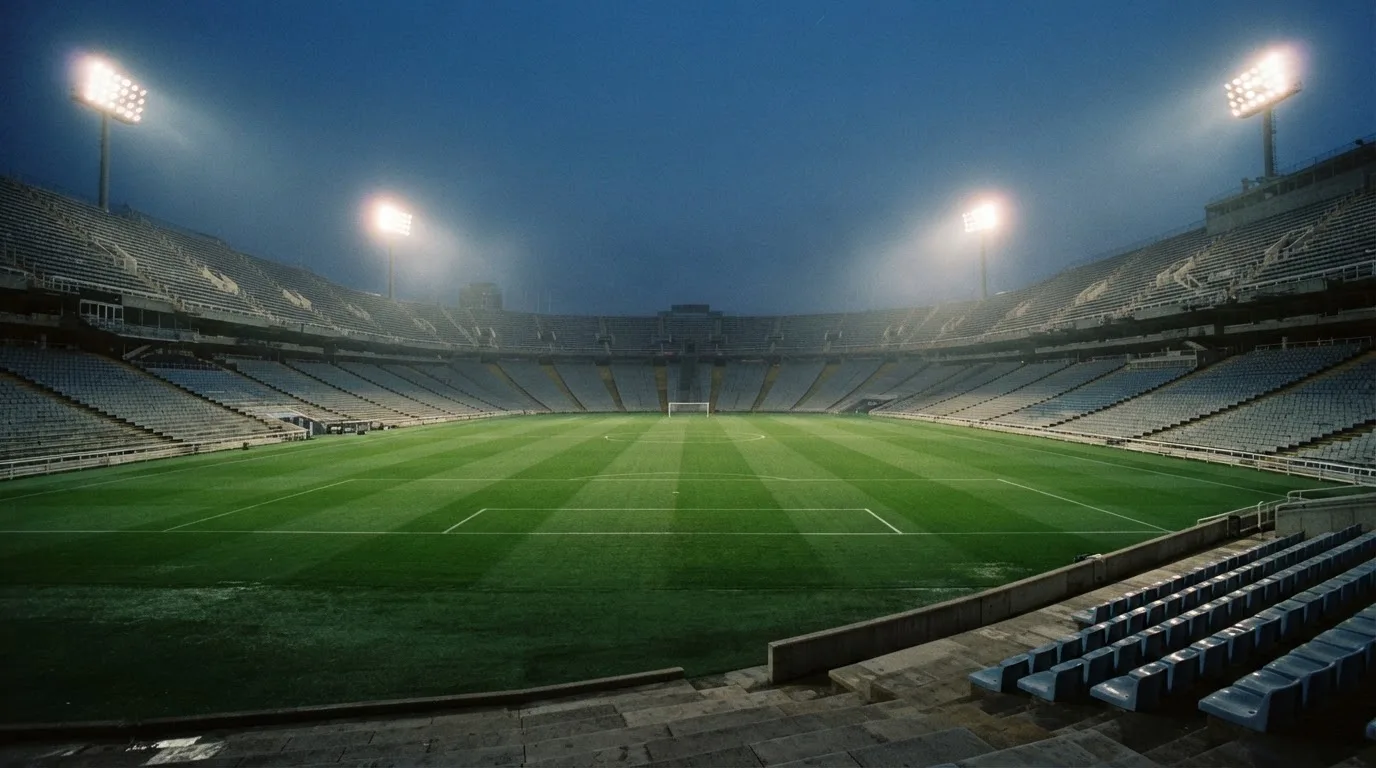 Een leeg voetbalstadion met lichtmasten bij schemering