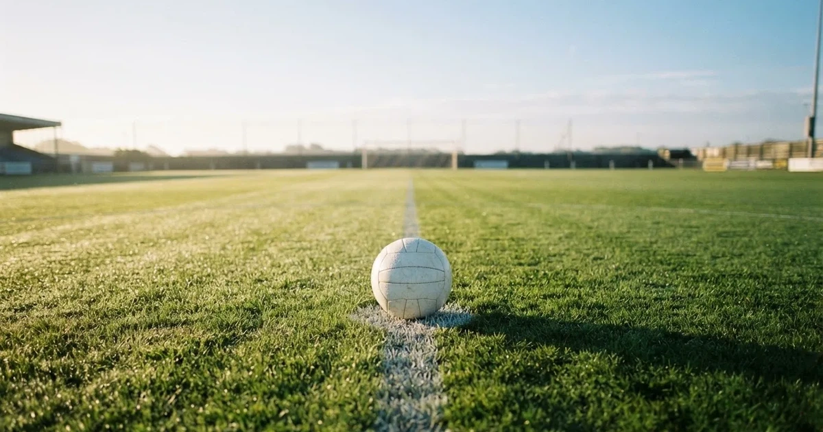 Een voetbal op de middenstip van een grasveld in het ochtendlicht