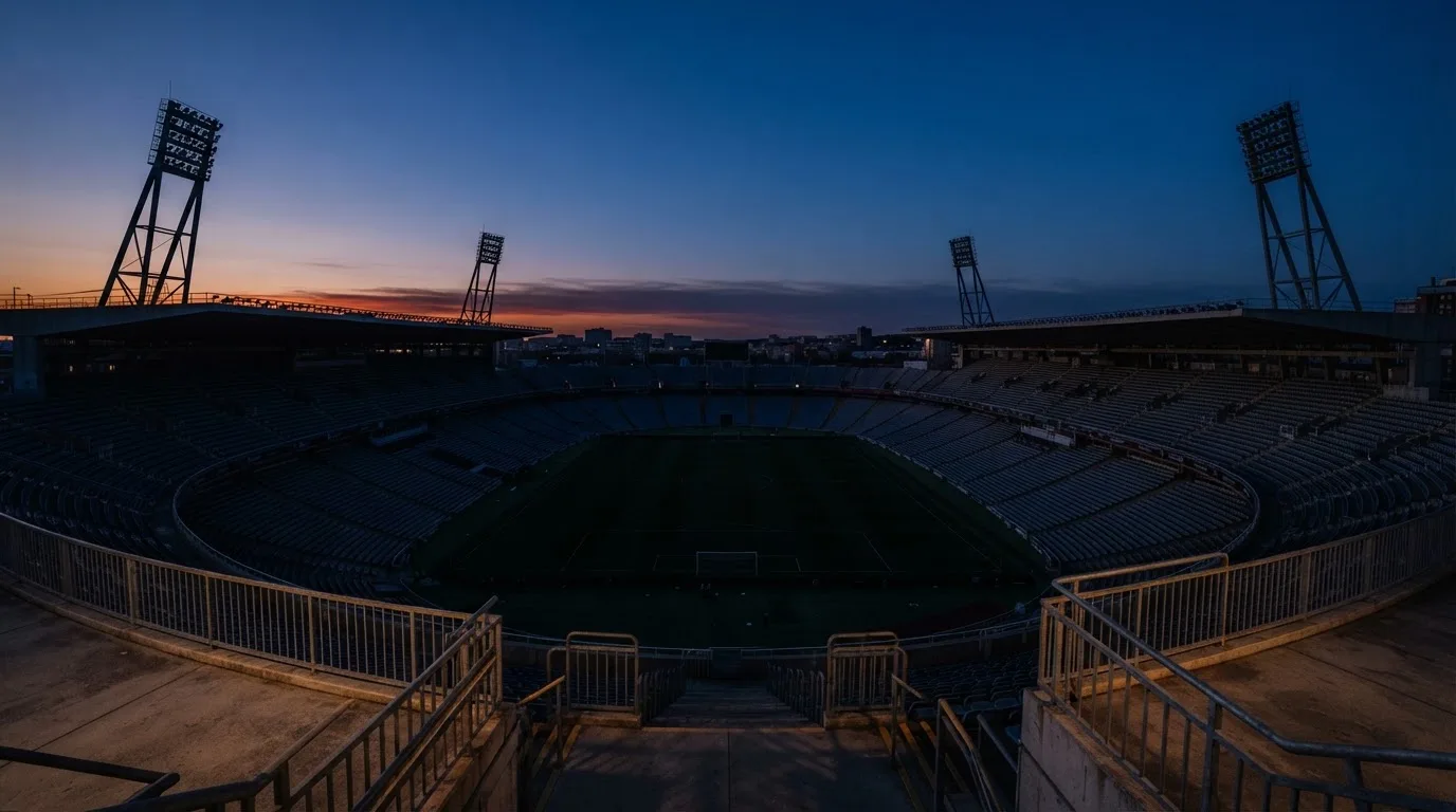 Een leeg voetbalstadion met lichtmasten bij schemering