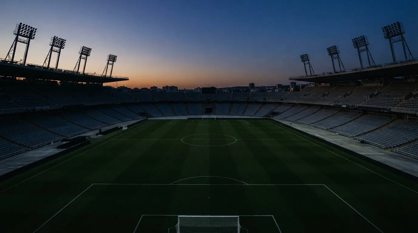 Een leeg voetbalstadion met lichtmasten bij schemering