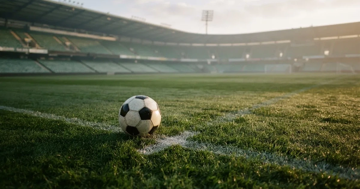 Een voetbal op de middenstip van een grasveld in het ochtendlicht